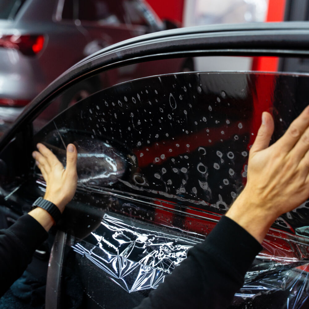 Manual stretching of dark tint film. Hand tensioning of window film removes air bubbles and ensures uniform coverage. Side window film hand stretching ensures flawless, wrinkle-free installation.